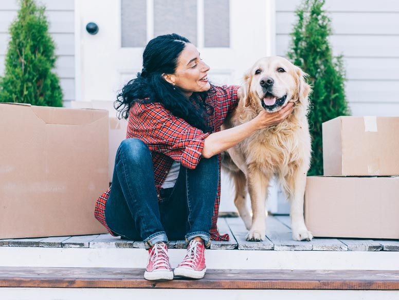 Woman with moving boxes on porch with dog